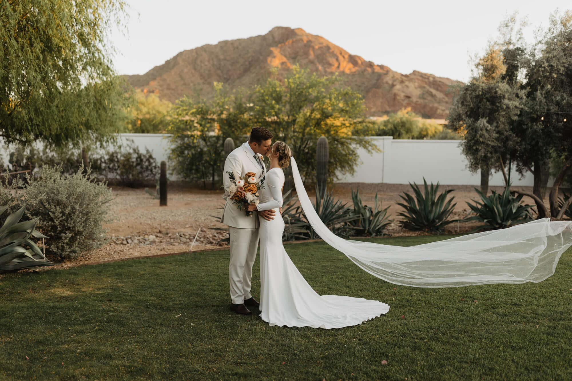Bride and Groom go in for a kiss as the Arizona sun sets in the background