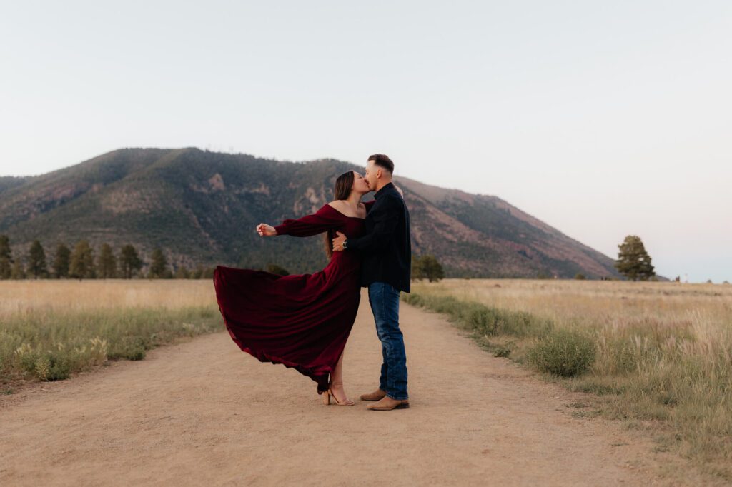 Bride to-be playfully tossing her dress as she shares a romantic kiss with her groom-to-be.