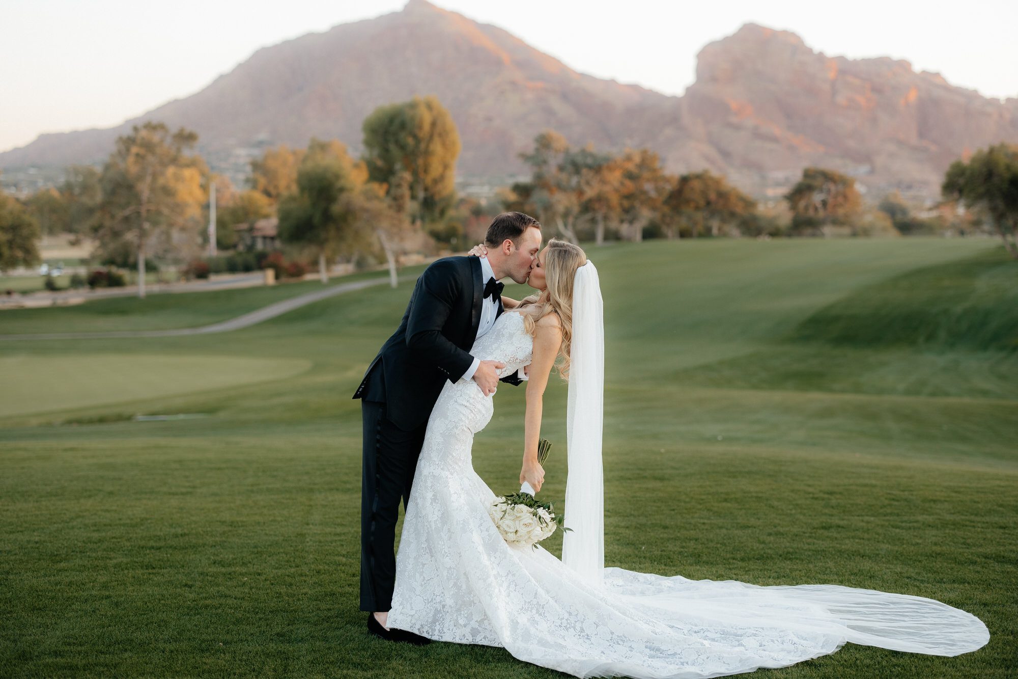 Groom Dip his bride and kisses her in front of Camleback Mountain at Paradise Valley Country Club wedding.