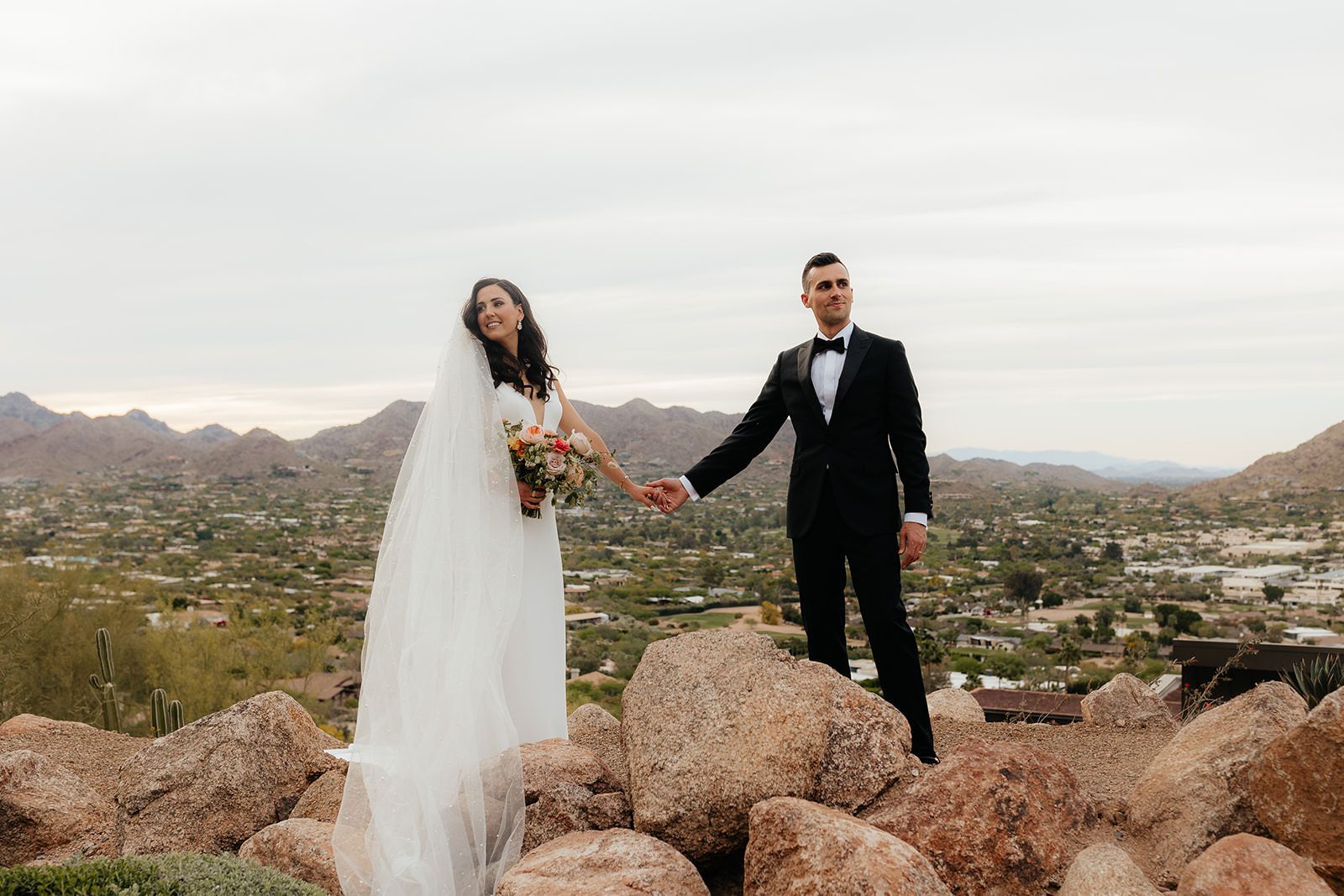 Bride and groom holding hands on Camelback Mountain at Sanctuary on Camelback wedding venue in Paradise Valley, Arizona.