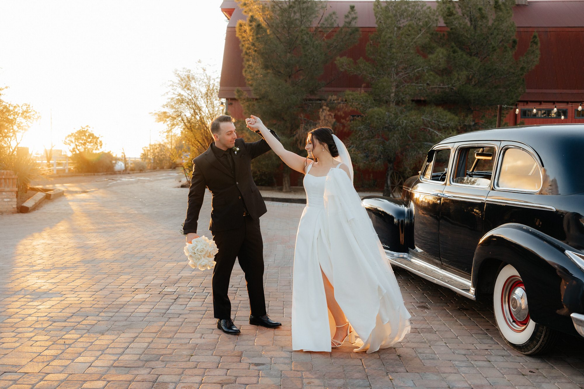 Groom twirling bride next to vintage car at Windmill Winery