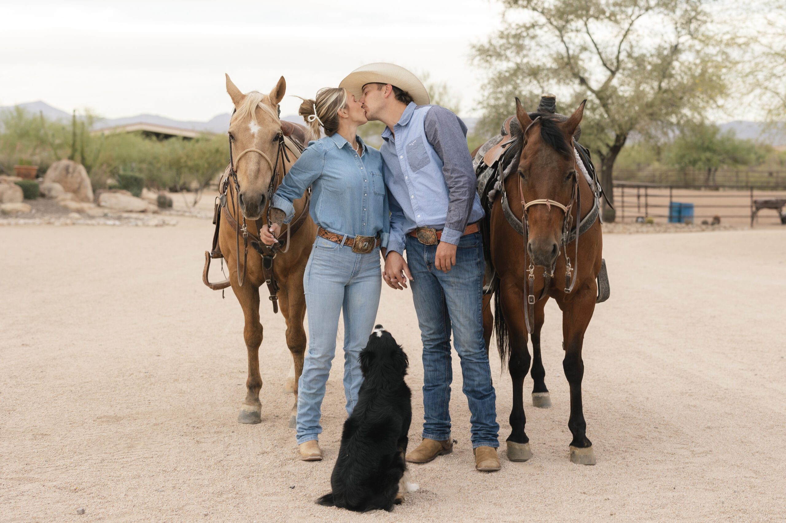 Couple kissing next to dog and their horses